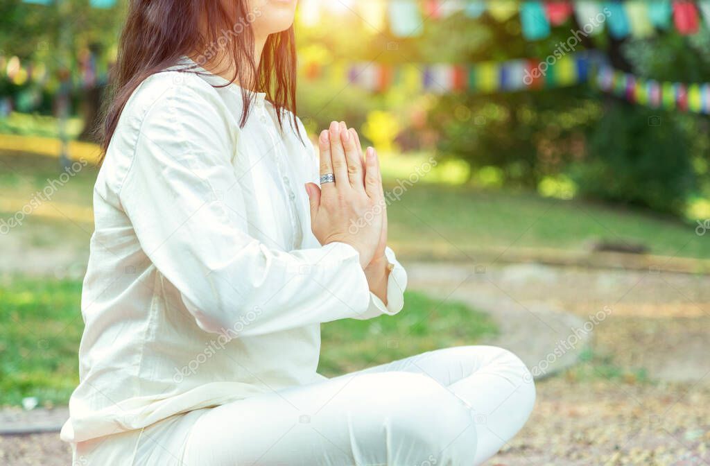 Close up of a woman in yoga and meditation outdoors in a park.
