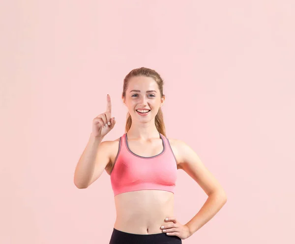 Mladá Fitness Žena Ukazuje Prstem Vzhůru Stojí Světle Růžovém Pozadí — Stock fotografie