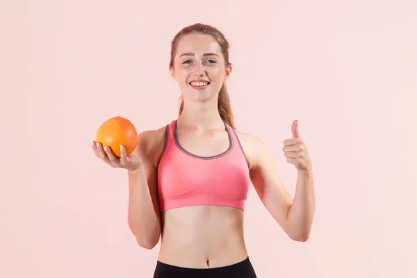 Mladá Sportovní Žena Drží Rukou Grapefruit Ukazuje Palec Nahoru Zatímco — Stock fotografie