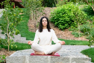 Genç bir kadın, doğa parkında, temiz havada meditasyon yapıyor..