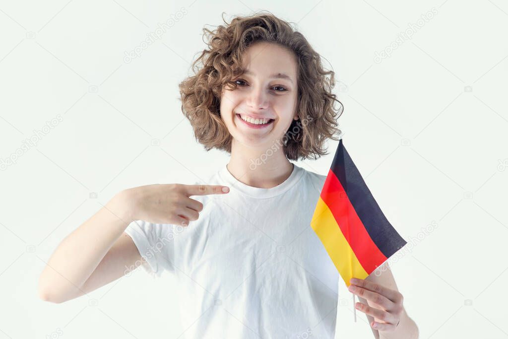 Young woman with the flag of Germany points a finger, looking at the camera.