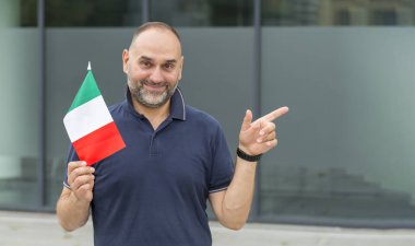 İtalya bayrağı taşıyan mutlu orta yaşlı adam parmağını fotokopi alanının kenarına doğrultuyor..