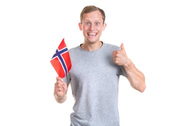 Norveç bayrağı taşıyan mutlu genç adam başparmağını kaldırır, kameraya bakar ve beyaz bir arka planda izole edilir..
