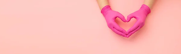 Teşekkürler, doktorlar. Metin için fotokopi alanı olan yatay afiş. Kırmızı eldivenli kadın elleri pembe arka planda kalbin sembolünü gösteriyor..