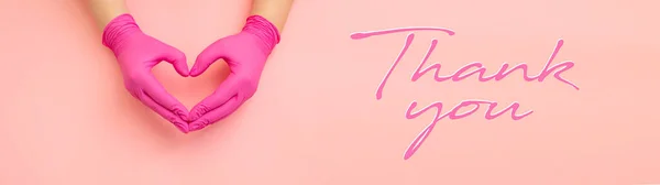 Thanks you doctors - horizontal banner with copy space for text. Female hands in red gloves show symbol of heart on pink background.
