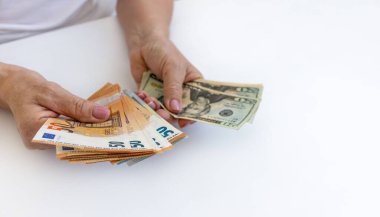 Hangi para biriminde tasarruf etmek daha iyidir? Avro ve dolarlarla olgun bir kadının elini kapat. Gelirinizi ve giderlerinizi sayın.