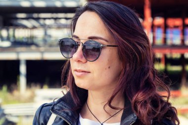 Deri ceketli ve güneş gözlüklü genç bir kadının portresi..