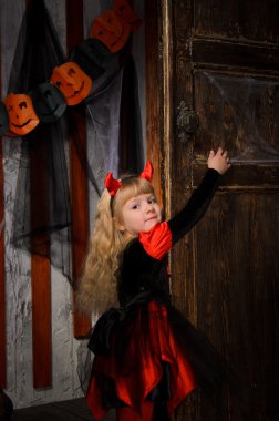 boynuzları kılık kırmızı ve siyah eski ahşap kapı kapalı kapatmak sarı saçlı Sevimli Cadılar Bayramı şeytan kız