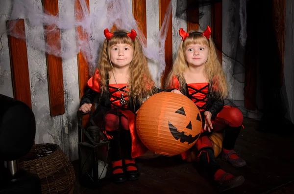 两个万圣节魔鬼女孩 小姐妹双胞胎 在黑色和红色的服装在室内的衣服角 — 图库照片