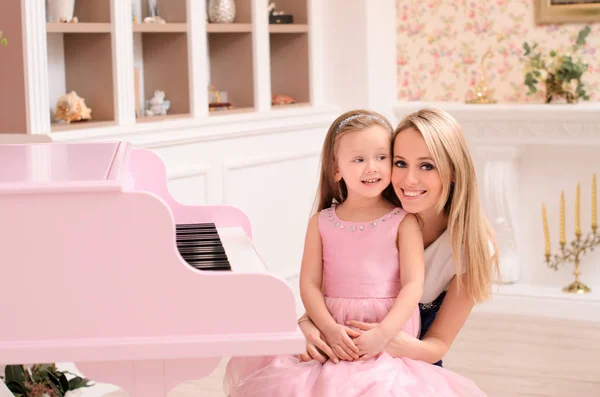 若い金髪の女性とインテリアで開かれたピンクのグランド ピアノで彼女の小さな娘の笑顔 — ストック写真