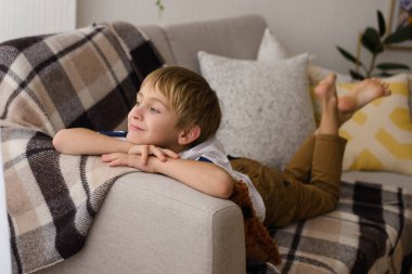 Evdeki odada kareli ekoseyle karnının üzerinde dinlenen güzel bir çocuğun portresi.
