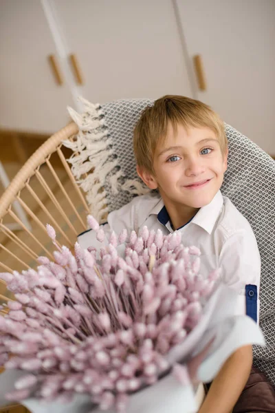 男孩穿着白衬衫 住在他家明亮的房间里 手里拿着一束鲜花送给妈妈的礼物 — 图库照片