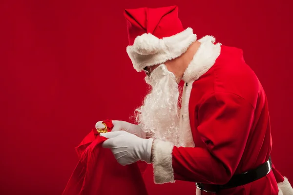 Santa claus avec gros sac sur épaule lunettes fond rouge — Photo