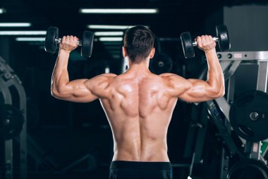 Spor, fitness, yaşam tarzı ve insanlar kavramı - kas vücut geliştirmeci adam spor salonunda dumbbells ile yapıyor.