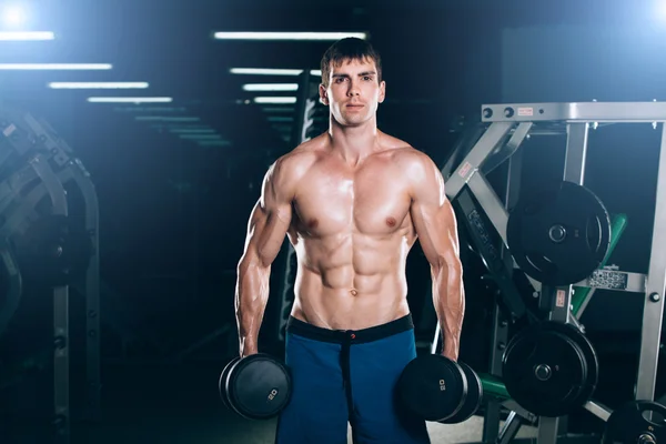 Spor, fitness, yaşam tarzı ve insanlar kavramı - kas vücut geliştirmeci adam spor salonunda dumbbells ile yapıyor — Stok fotoğraf