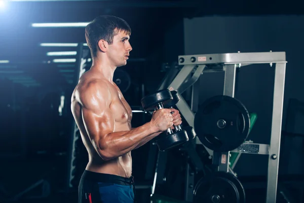 Sport, fitness, lifestyle and people concept - Muscular bodybuilder guy doing exercises with dumbbells in gym. — Stock Photo, Image