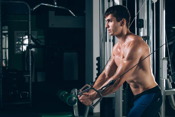 Apuesto culturista trabaja empujando hacia arriba el ejercicio en el gimnasio —  Fotos de Stock