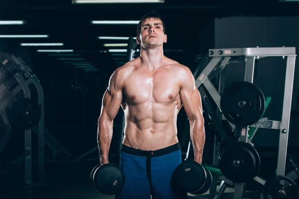 Deporte, fitness, estilo de vida y la gente concepto - Muscular culturista chico haciendo ejercicios con pesas en el gimnasio . — Foto de Stock