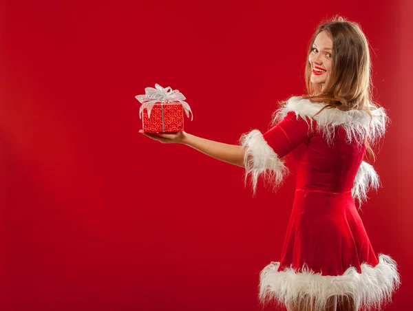 Natal, x-mas, inverno, conceito de felicidade - mulher sorridente em chapéu de Papai Noel ajudante com caixa de presente, sobre fundo vermelho . — Fotografia de Stock