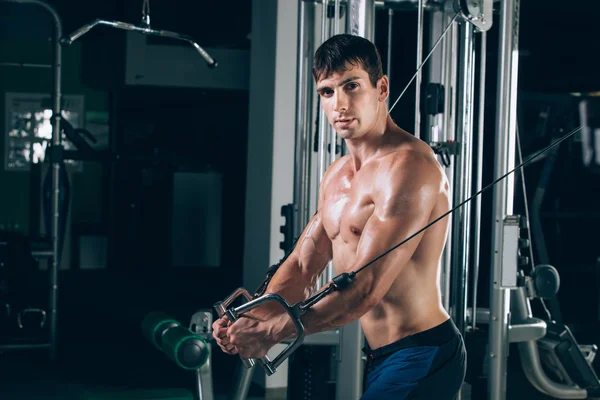 Apuesto culturista trabaja empujando hacia arriba el ejercicio en el gimnasio —  Fotos de Stock