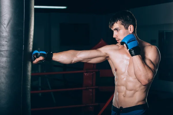 Boxeador masculino joven usando un saco de boxeo en el gimnasio . —  Fotos de Stock