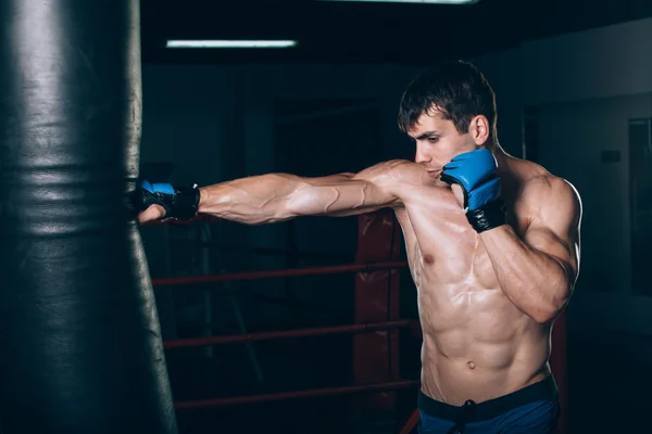 Junger Boxer mit Boxsack im Fitnessstudio. — Stockfoto