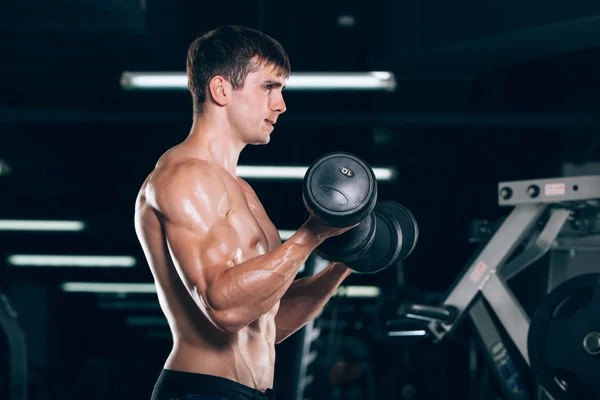 Sport, fitness, lifestyle and people concept - Muscular bodybuilder guy doing exercises with dumbbells in gym. — Stock Photo, Image