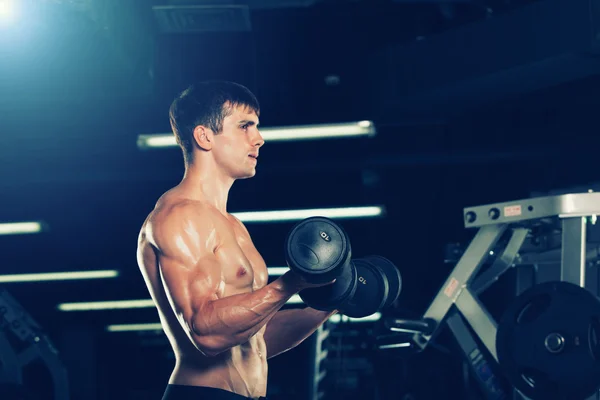 Sport, fitnesz, életmód és az emberek koncepció - testépítő izmos srác gyakorolja a súlyzók tornaterem. — Stock Fotó