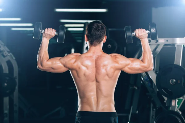 Spor, fitness, yaşam tarzı ve insanlar kavramı - kas vücut geliştirmeci adam spor salonunda dumbbells ile yapıyor. — Stok fotoğraf