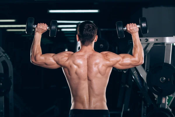 Spor, fitness, yaşam tarzı ve insanlar kavramı - kas vücut geliştirmeci adam spor salonunda dumbbells ile yapıyor. — Stok fotoğraf