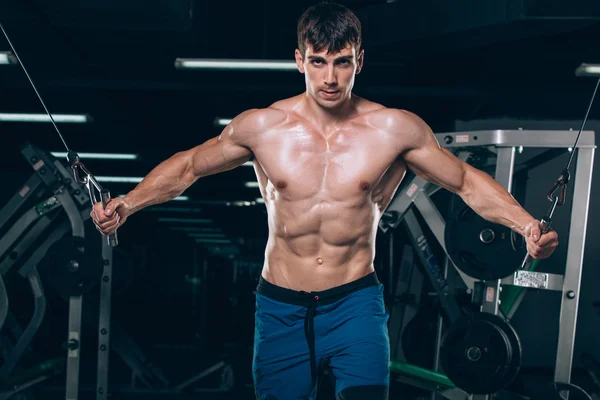 Apuesto culturista trabaja empujando hacia arriba el ejercicio en el gimnasio —  Fotos de Stock