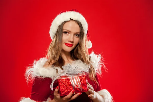 Natal, x-mas, inverno, conceito de felicidade - mulher sorridente em chapéu de Papai Noel ajudante com caixa de presente, sobre fundo vermelho — Fotografia de Stock