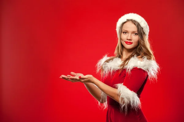 크리스마스, 엑스-마스, 겨울, 행복 개념-선물 상자, 산타 도우미 모자에 여자 앞에 제공 하 고, 그의 손을 잡고 웃 고는, 빨간색 배경 위에. — 스톡 사진