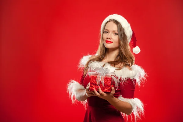 Natal, x-mas, inverno, conceito de felicidade - mulher sorridente em chapéu de Papai Noel ajudante com caixa de presente, sobre fundo vermelho — Fotografia de Stock