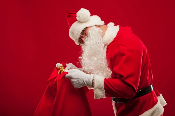 Santa claus with big bag on shoulder glasses  red background — Stock Photo, Image