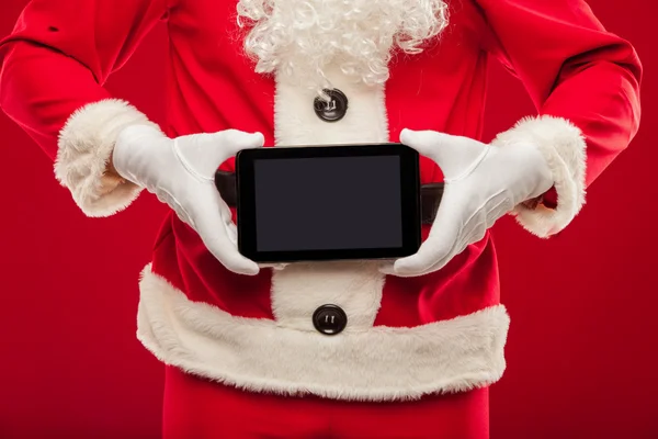 サンタ クロースがタブレットを保持しています。赤い背景、手 — ストック写真
