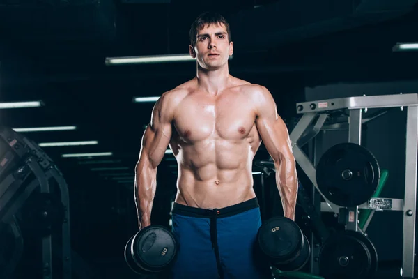 Sport, fitness, livsstil och människor koncept - muskulös bodybuilder killen gör övningar med hantlar i gymmet. — Stockfoto