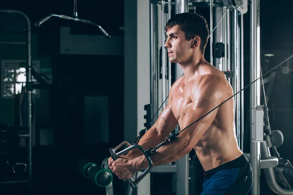 Apuesto culturista trabaja empujando hacia arriba el ejercicio en el gimnasio —  Fotos de Stock