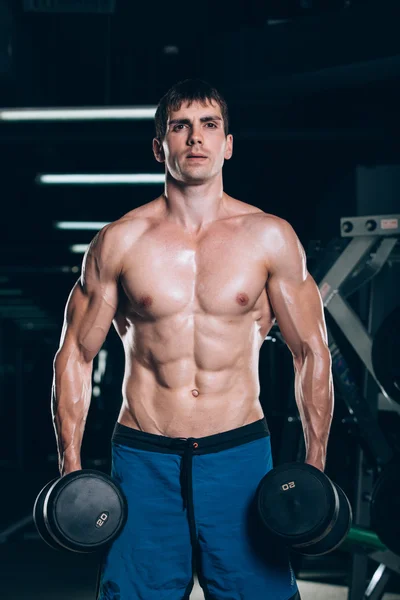 Spor, fitness, yaşam tarzı ve insanlar kavramı - kas vücut geliştirmeci adam spor salonunda dumbbells ile yapıyor. — Stok fotoğraf