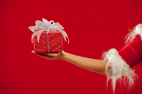 Christmas. Photo of Santa Claus gloved hand with red gift box