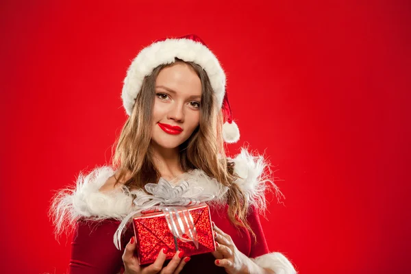 Natal, x-mas, inverno, conceito de felicidade - mulher sorridente em chapéu de Papai Noel ajudante com caixa de presente, sobre fundo vermelho — Fotografia de Stock