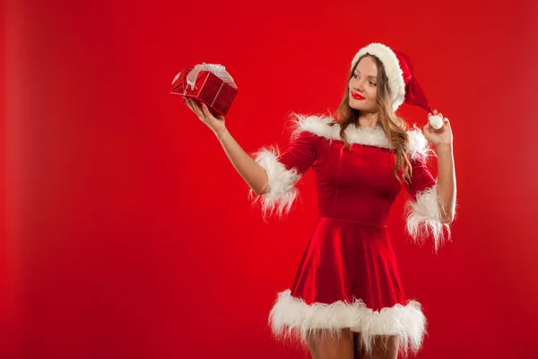 Natal, x-mas, inverno, conceito de felicidade - mulher sorridente em chapéu de Papai Noel ajudante com caixa de presente, sobre fundo vermelho — Fotografia de Stock