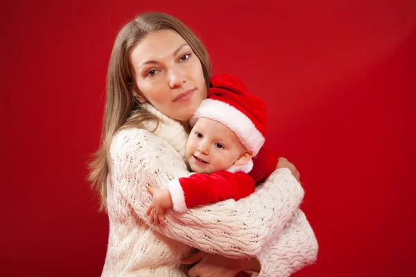 Feliz joven madre con su dulce bebé en un traje de Navidad rojo —  Fotos de Stock