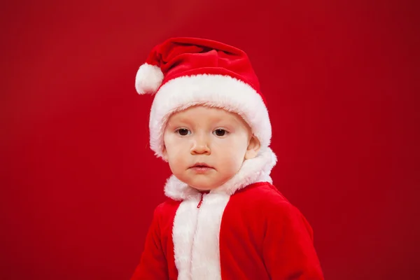 Beautiful little baby celebrates Christmas. New Years holidays red background — Stockfoto