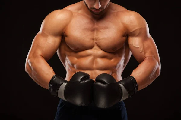 Muscolare giovane uomo con perfetto busto con sei pack abs, in guantoni da boxe sta mostrando i diversi movimenti e colpi isolati su sfondo nero con copyspace — Foto Stock