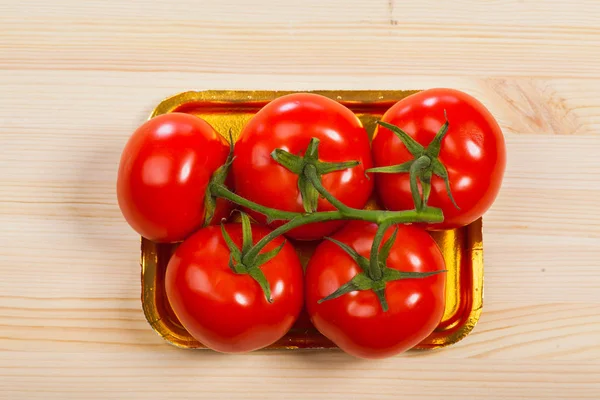 Five fresh red tomatoes with green stem in the tray , isolated on the background — Stock Photo, Image