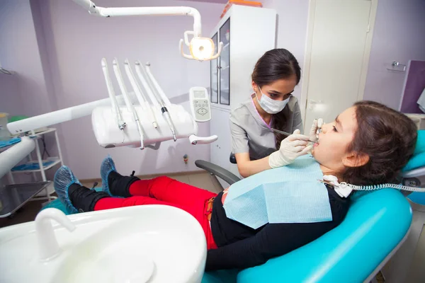 Красива маленька дівчинка відкриває рот широко під час лікування зубів стоматологом — стокове фото