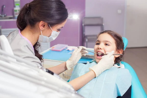 Nahaufnahme eines hübschen kleinen Mädchens, das seinen Mund weit öffnet, während der Zahnarzt ihre Zähne behandelt — Stockfoto