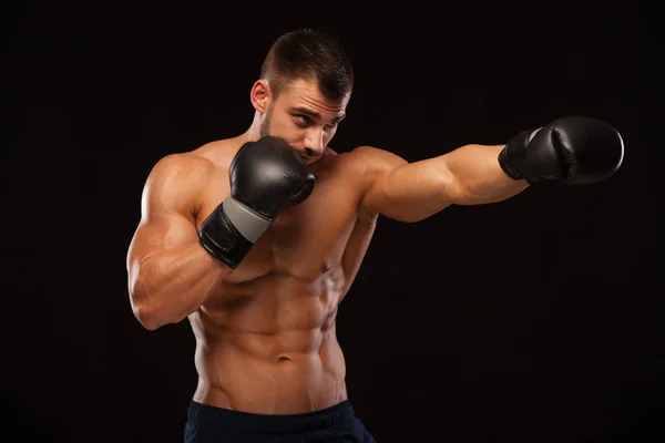 Joven musculoso con torso perfecto con seis abdominales, en guantes de boxeo está mostrando los diferentes movimientos y golpes aislados sobre fondo negro con copyspace —  Fotos de Stock