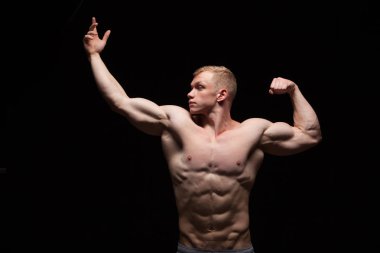 Atletik yakışıklı adam fitness-modeli altı bohça abs gösterilen ve sol tarafta arıyorum. siyah arka plan ile boşaltmak izole